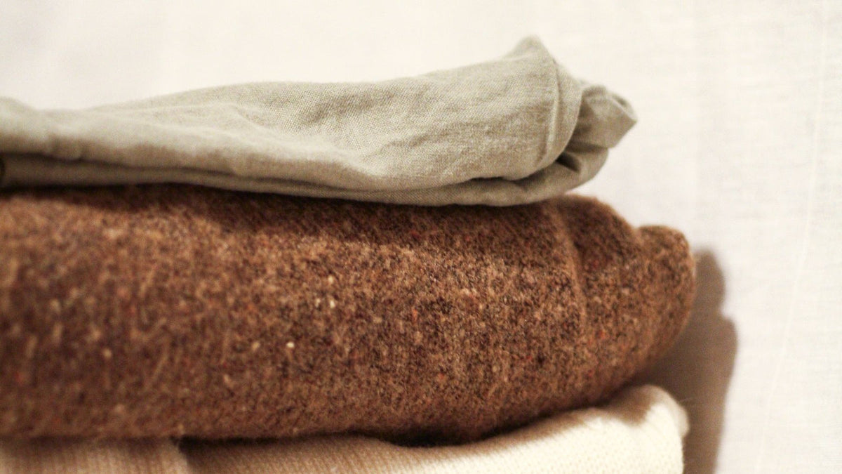A stack of folded neutral garments in soft light, used as an illustrative care image.