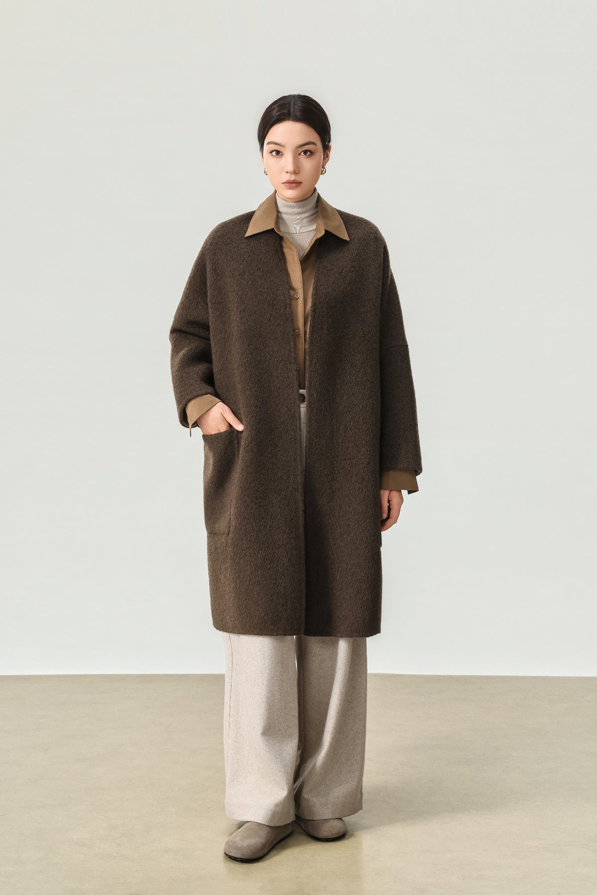 Front view of the dark brown wool and yak-blend coat, worn over a brown shirt and cream trousers.