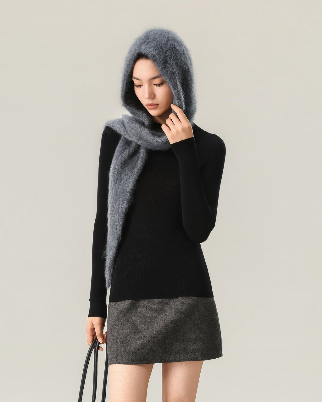 Grey one-piece hooded scarf worn with the hood up and long tapered ends wrapped and draped, in portrait framing.