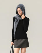 Grey one-piece hooded scarf worn with the hood up and long tapered ends wrapped and draped, in portrait framing.