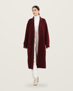 Burgundy wool coat worn with ivory knitwear, trousers and boots.