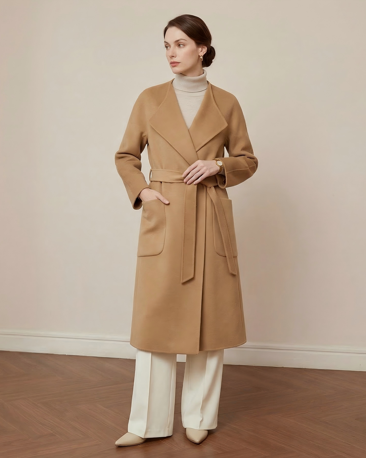 Camel wool wrap coat with a tie belt and patch pockets, worn with ivory knitwear and trousers.
