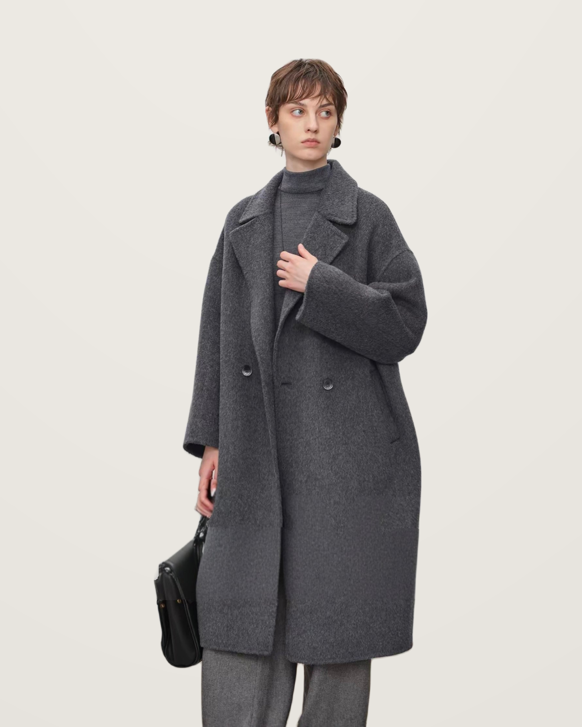 Grey wool coat with broad lapels, worn with grey knitwear and trousers.