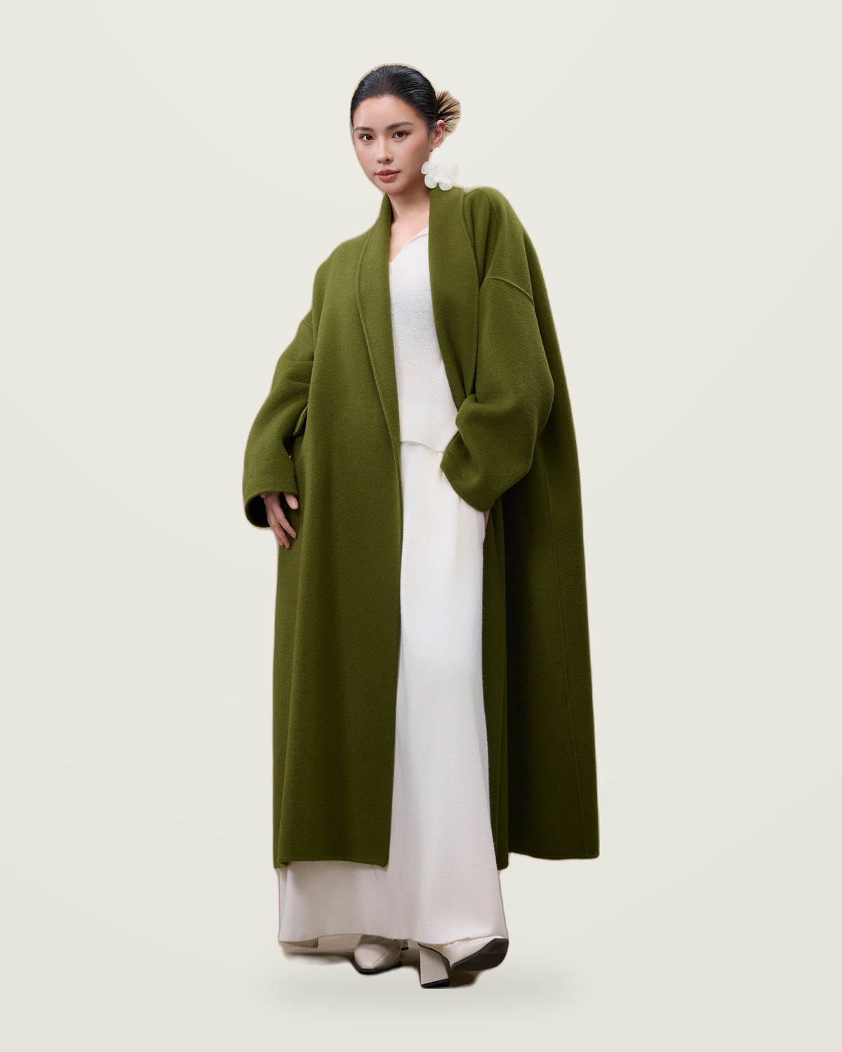 Green wool coat with wide sleeves, worn over a white top and long skirt.
