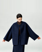 AI-assisted styling of THE LANE 007 Navy pure wool oversized short coat, round neckline, dropped shoulders and wide sleeves. Arms extended to show the silhouette.