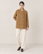 AI-assisted styling of THE LANE 25219 Brown straight-cut coat, relaxed front view with all eight buttons fastened; cream trousers and chocolate-brown ankle boots.