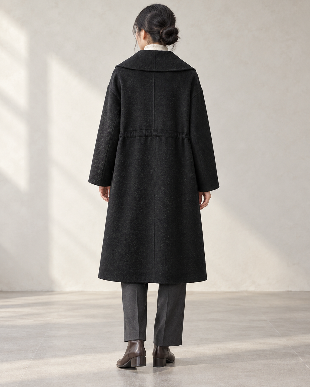 Vienna coat in Black, relaxed rear model view with centre back seam and integral drawcord channel — AI-assisted styling image.