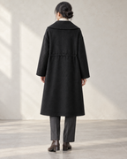 Vienna coat in Black, relaxed rear model view with centre back seam and integral drawcord channel — AI-assisted styling image.