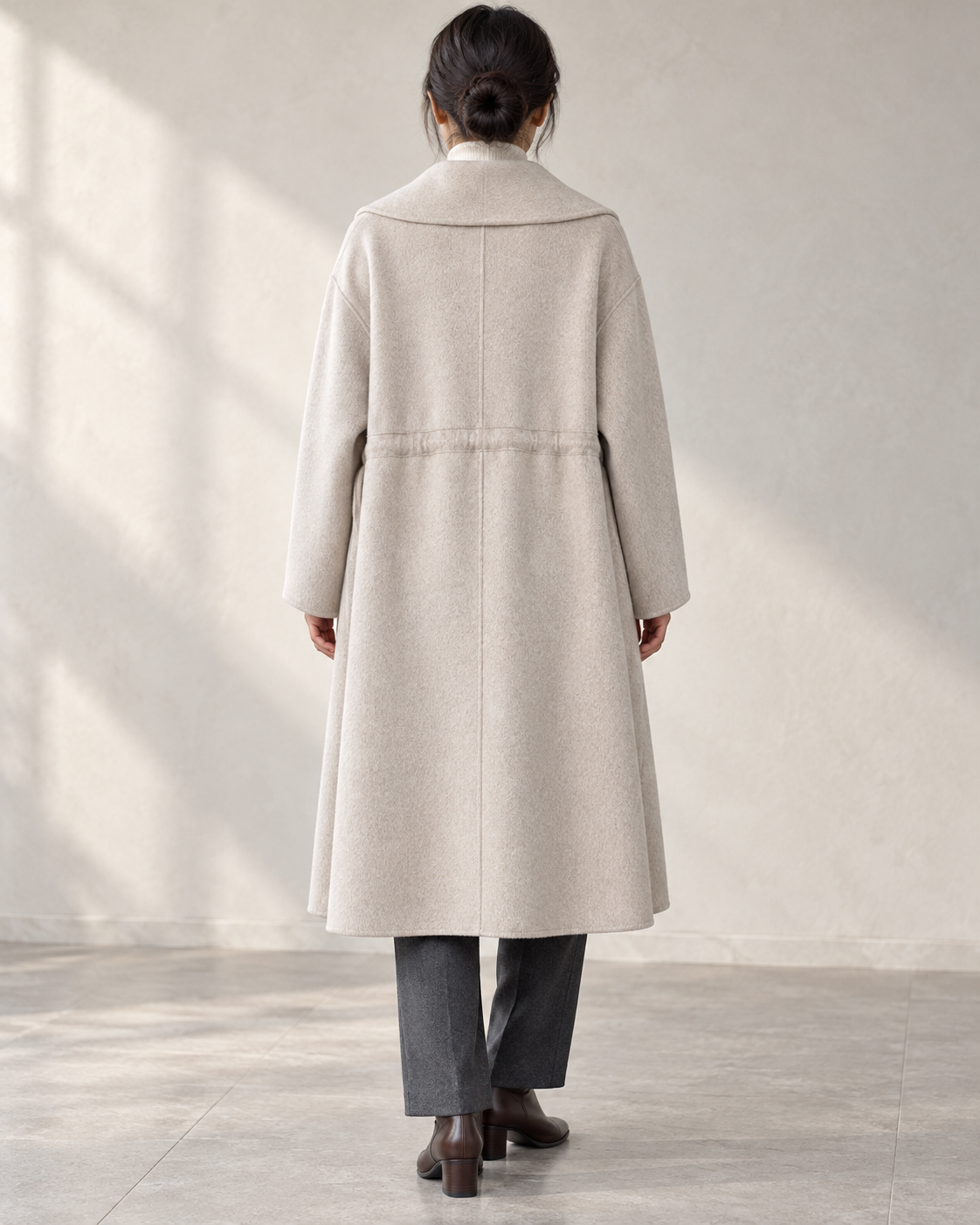 Vienna coat in Oats, relaxed rear model view with centre back seam and integral drawcord channel — AI-assisted styling image.