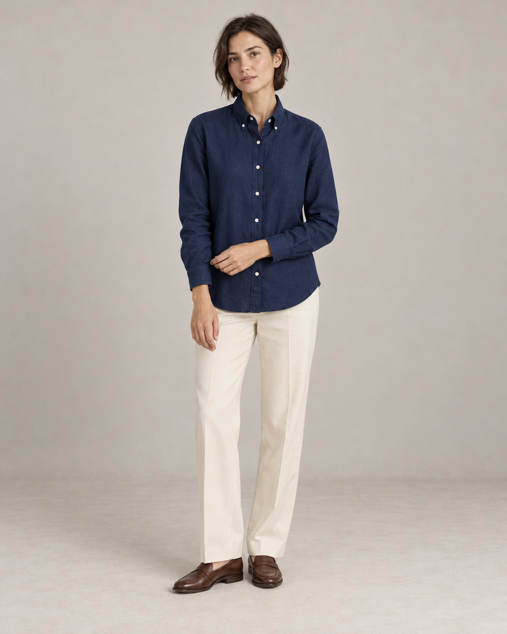 Navy linen shirt worn untucked at the hip with ivory trousers and brown loafers. AI-assisted styling based on supplied garment and textile photographs.