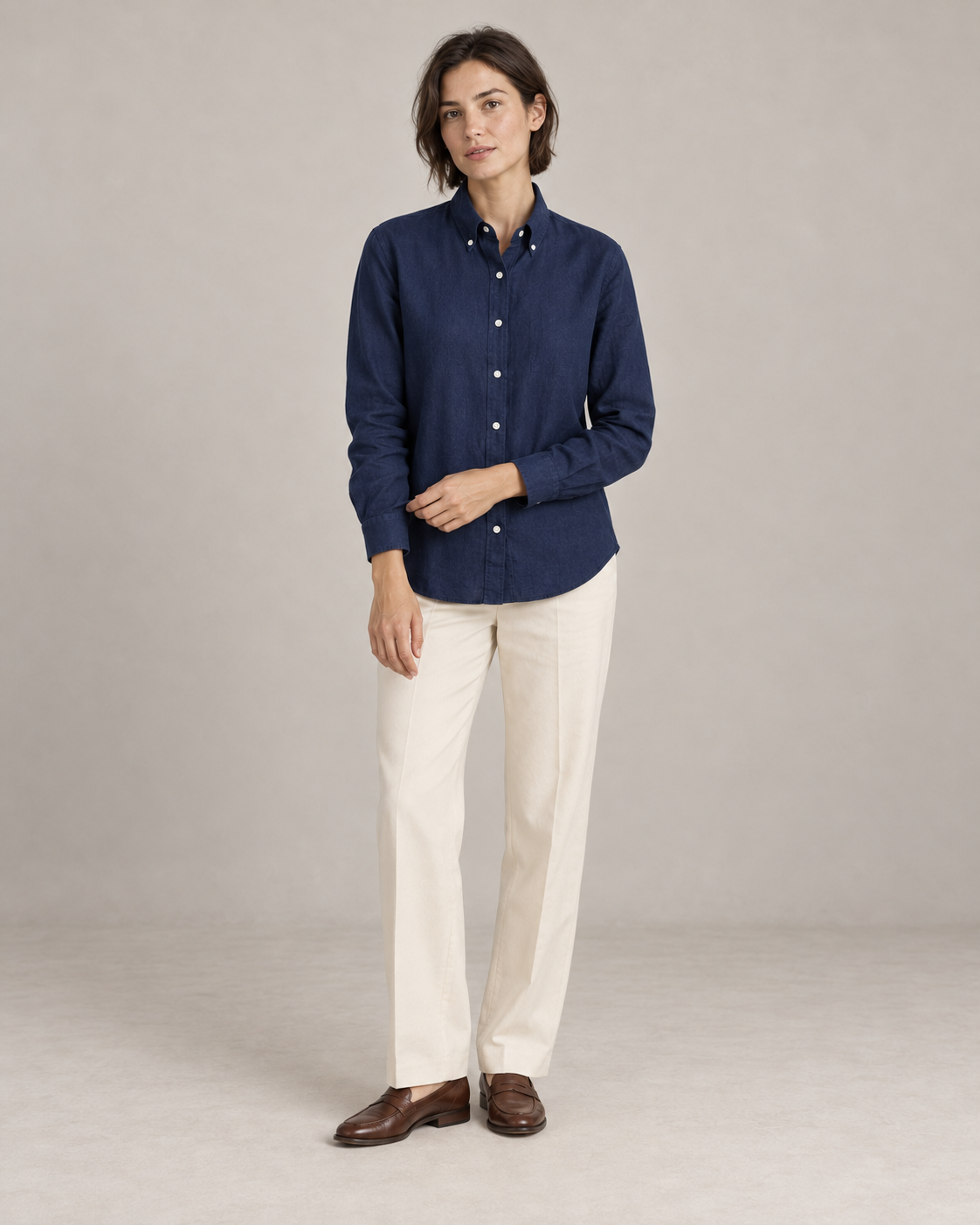 Navy linen shirt worn untucked at the hip with ivory trousers and brown loafers. AI-assisted styling based on supplied garment and textile photographs.
