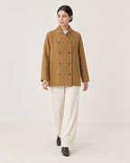 AI-assisted styling of THE LANE 25219 Brown straight-cut coat, walking front view with all eight buttons fastened; cream trousers and chocolate-brown ankle boots.