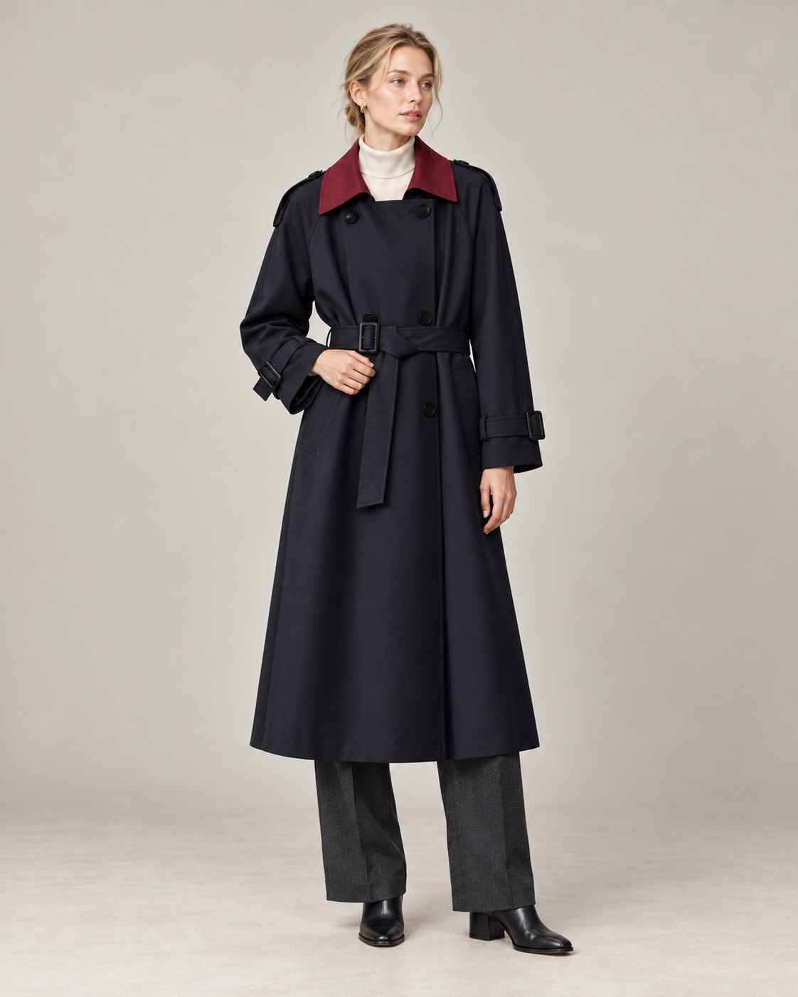 Navy trench coat with burgundy contrast collar and a buckled belt, worn with charcoal trousers and black leather boots. AI-assisted styling based on supplied garment and textile photographs.